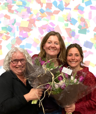 Drie vrouwen met stralende glimlach en bossen bloemen. Confetti op de achtergrond.